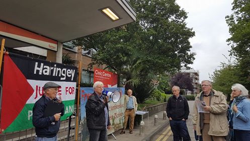 Professor Haim Bresheeth addresses the protest outside the Council Meeting, in front of the FSOI banner